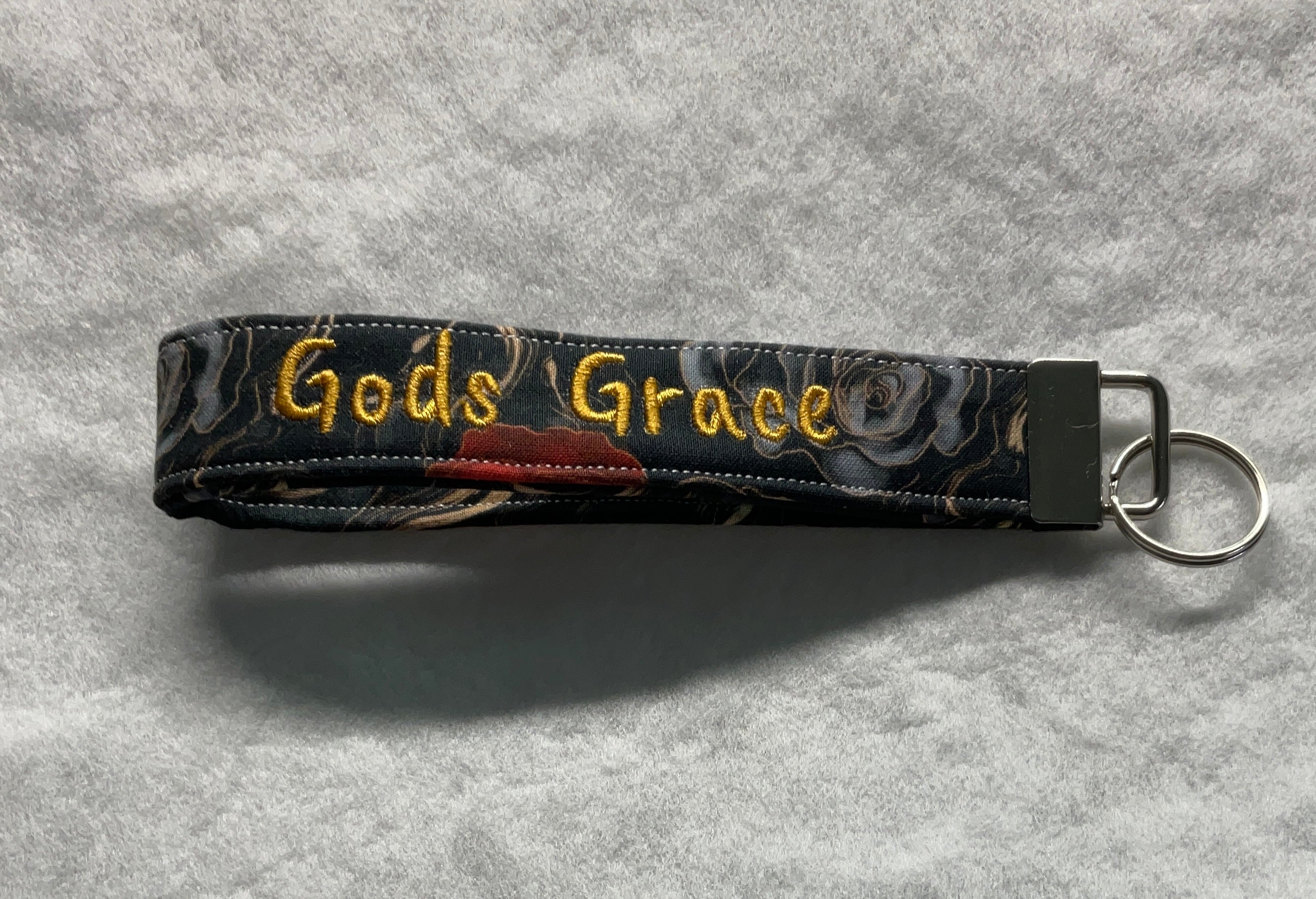 Keychain with 'God's Grace' embroidery on a floral patterned strap 