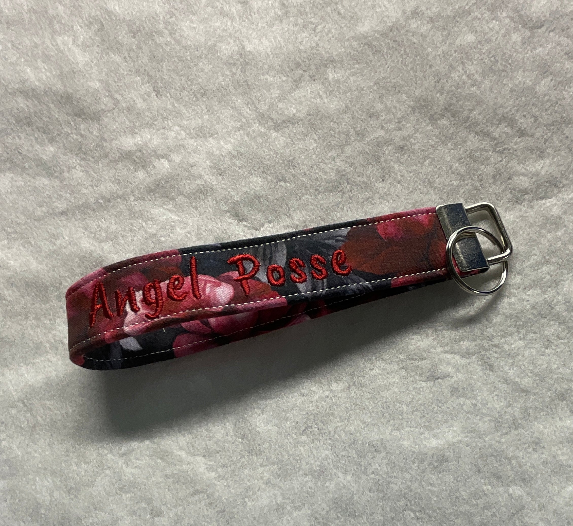 Floral patterned keychain with 'Angel Posse' embroidery