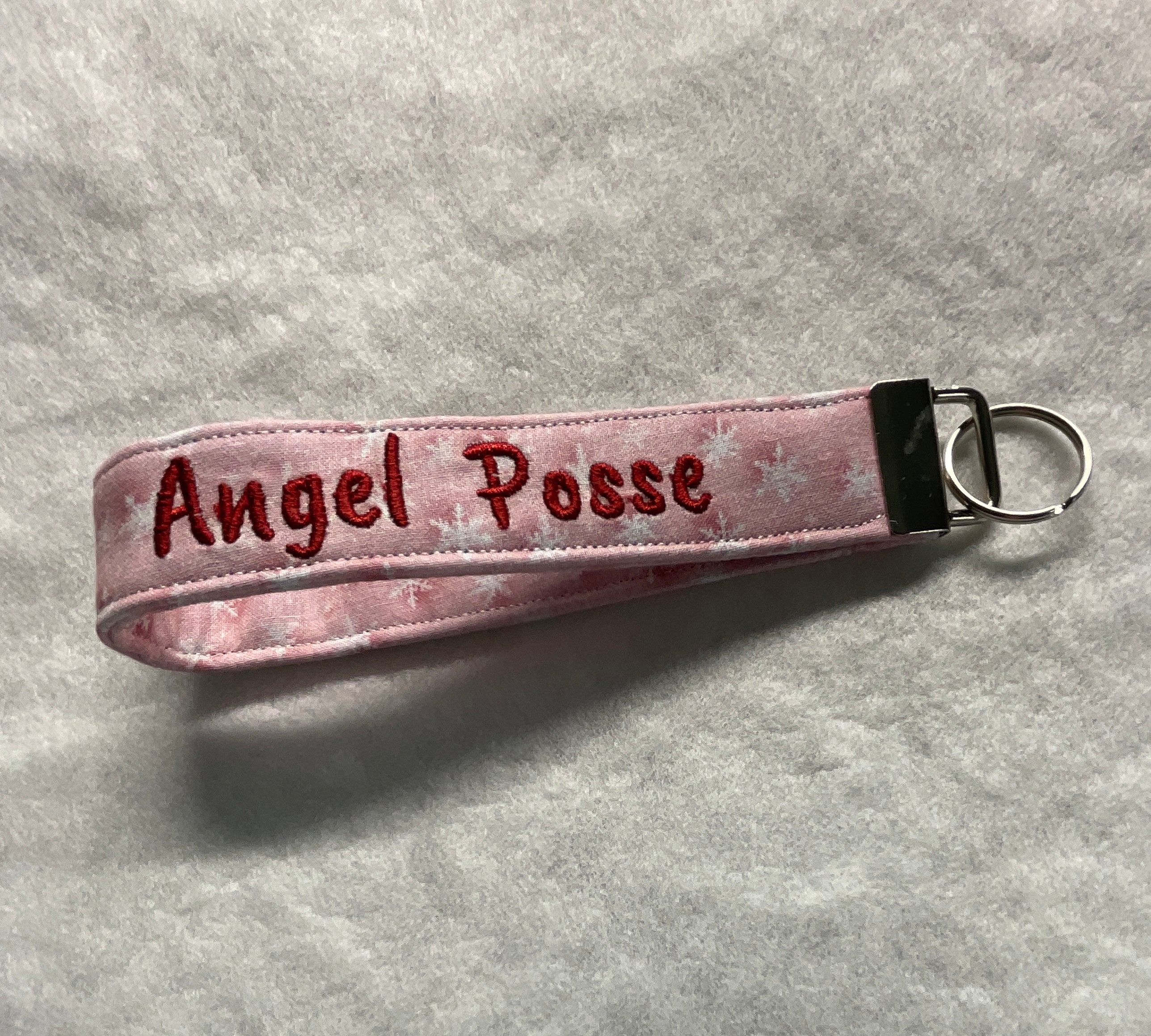 Pink wristlet keychain with 'Angel Posse' embroidery