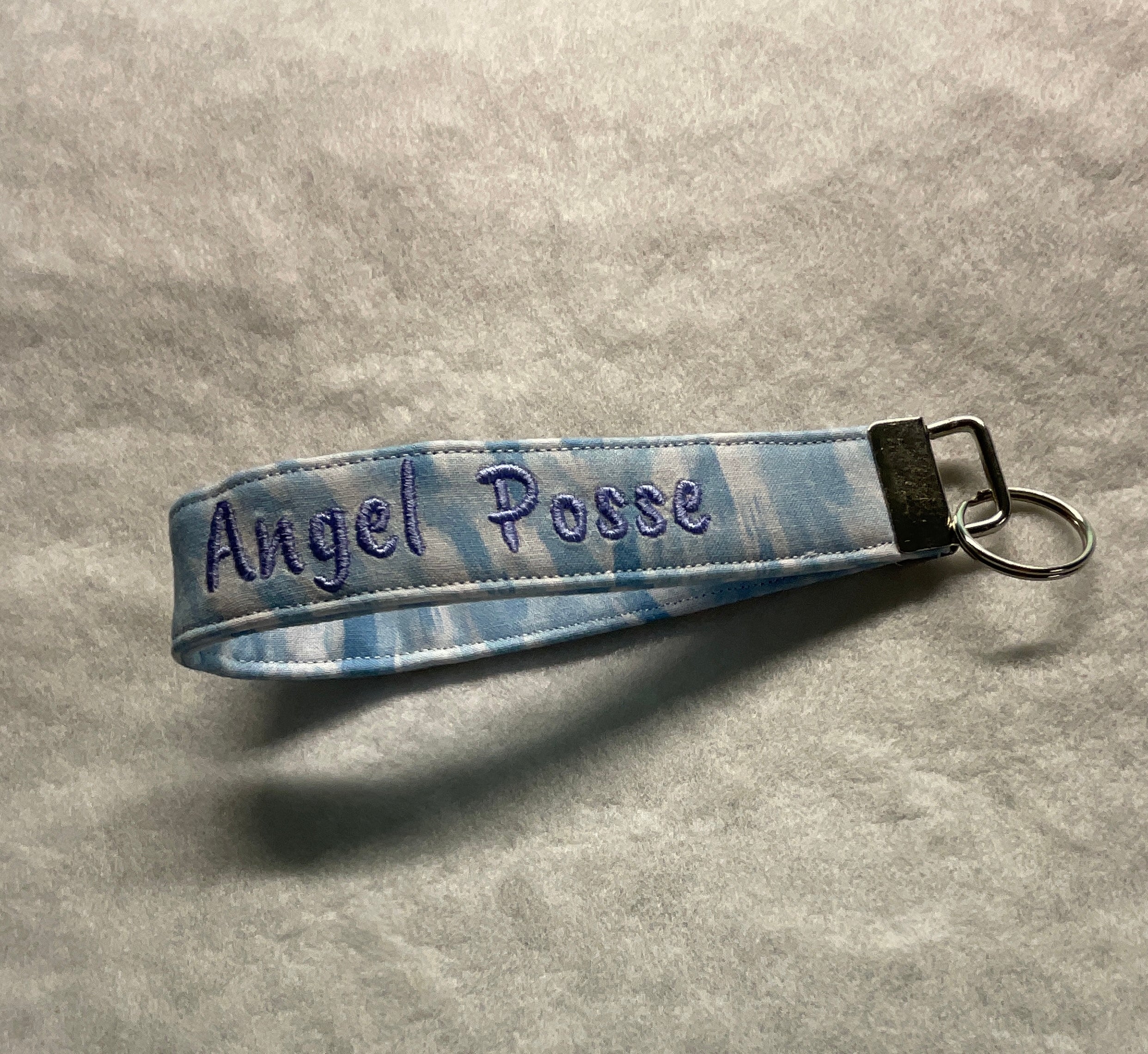 Blue striped keychain with 'Angel Posse' embroidery