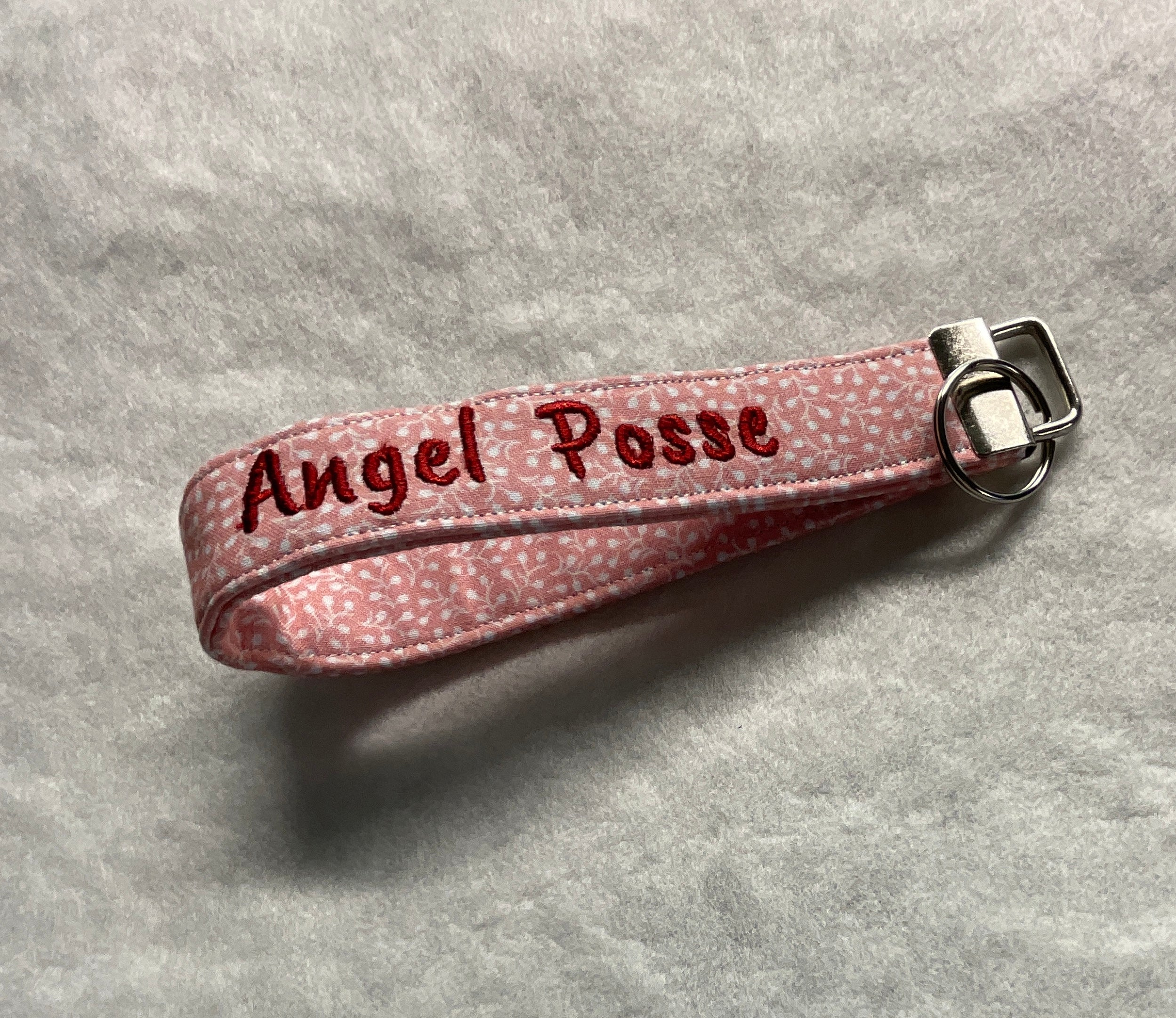 Pink keychain with 'Angel Posse' embroidery